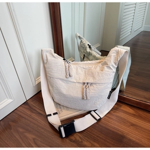Detail of off-white nylon crossbody bag with woven zipper cords and black plastic buckle