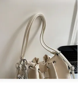 Detail of cream drawstring bucket bag showing durable handles and heart charm accessory