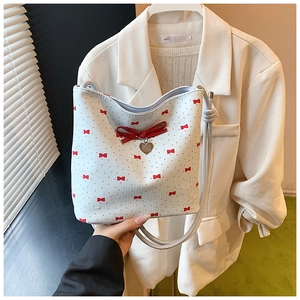 Detail shot of white PU shoulder bag featuring red bow prints and a 3D heart pendant