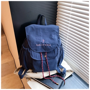 Gros plan sur le sac à dos en toile bleu marine avec broderie rose et détails de nœuds