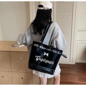 Gros plan sur un sac fourre-tout noir brillant avec motif nœud et boucles métalliques