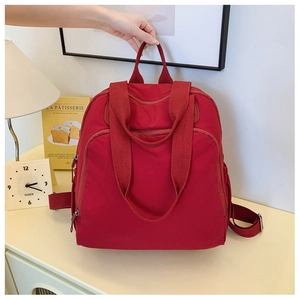 Detalle de mochila de nailon rojo resistente al agua con varios bolsillos y correas anchas