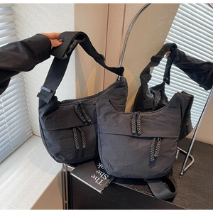 Detail view of large and small black canvas crossbody bags with woven zippers and brand label