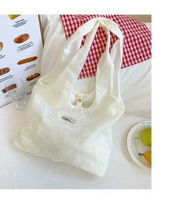 Detailed close-up of white canvas tote bag featuring delicate floral embroidery and tag