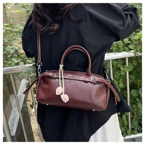 Detail of burgundy lychee leather handbag featuring silver hardware and tulip charm