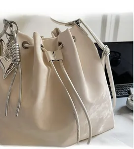 Close-up of cream drawstring bucket bag with silver heart charms and leather texture