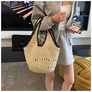 Detail of a handmade beige straw tote bag with black woven trim and hollow stripes