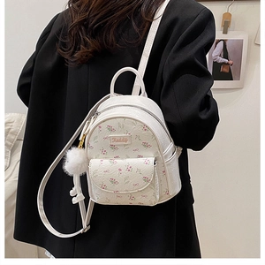 Dettaglio dello zaino bianco a fiori in pelle con ciondolo a pompon su modella