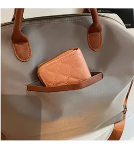 Détail du sac cabas gris avec poche avant contenant un portefeuille rose matelassé