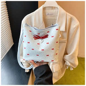 Detail of white bucket bag with red bows, heart charm and sleek faux leather finish