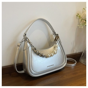Détail du sac croissant argenté avec chaîne cœur en perles et texture cuir