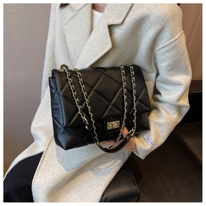 Detail of black quilted leather shoulder bag with gold chain strap and twist lock closure