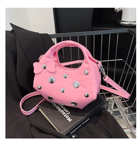 Sac seau en cuir verni rose avec rivets et nœud placé dans un chariot en métal