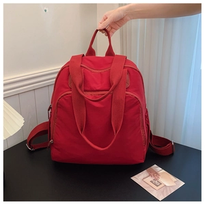 Detalle del nailon rojo brillante y las asas de transporte de esta mochila versátil de mujer