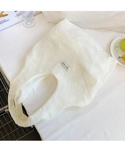 Detail of minimalist cream canvas tote bag with unique crinkled texture and woven label