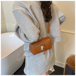 Close-up of small brown leather crossbody bag with cute silver robot charm accessory