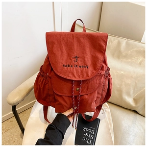 Détail d'un sac à dos en nylon rouge rouille avec broderie et poches à cordon