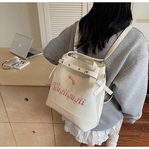 Détail du sac à dos crème avec broderie de nœud rose et lettrage artistique Gugügugü