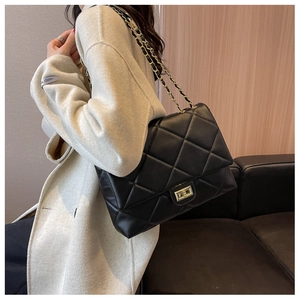Detailed macro shot of the black quilted texture and golden twist lock on this shoulder bag