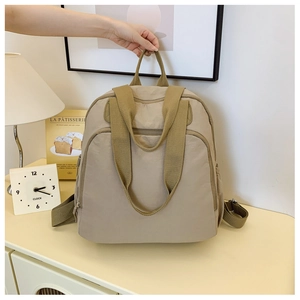 Primer plano del detalle de mochila beige con textura de nailon y asa superior