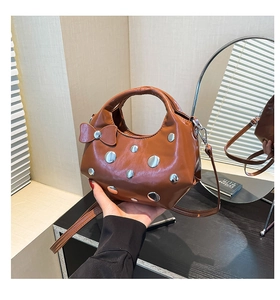 Vue détaillée du sac à bandoulière marron avec rivets métalliques et breloque noeud en cuir