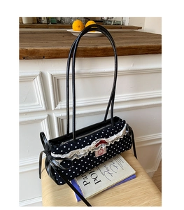 Détail du sac à pois noir rétro avec dentelle blanche et petit nœud rouge élégant