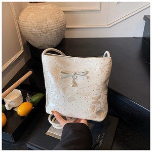 Detail of cream bow shoulder bag with butterfly print and pearl charm on black steps