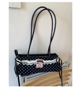 Détail du sac à pois noirs avec bordure en dentelle blanche et noeud rouge