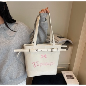 Détail d'un grand sac cabas blanc avec broderie nœud rose et boucles en métal argenté