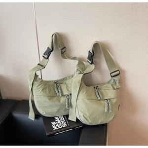 Detail of light olive nylon crescent bag featuring double zippers and black buckle strap