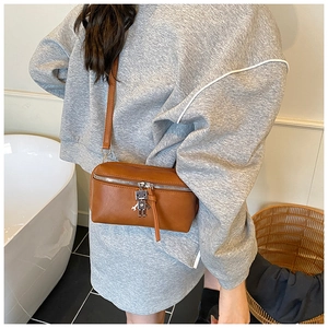 Brown leather crossbody bag with silver robot charm and zipper detail on shoulder