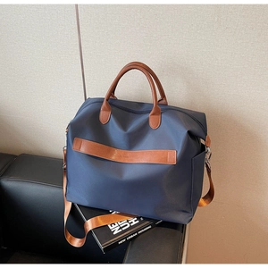 Détail du sac de voyage en nylon bleu marine avec poignées en cuir marron et gaufrage N. 008