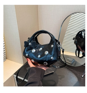 Détail du sac en cuir verni noir brillant avec rivets argentés et nœud décoratif