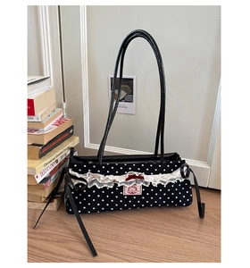 Détail du sac bandoulière noir à pois avec dentelle blanche et nœud en velours rouge