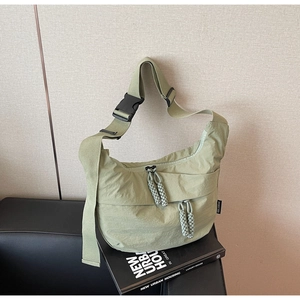 Detail of light green nylon crossbody bag with black buckle and durable wide strap