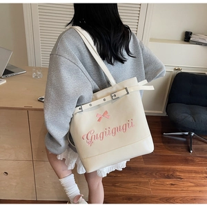 Détail du sac fourre-tout crème avec broderie nœud rose et ceinture décorative