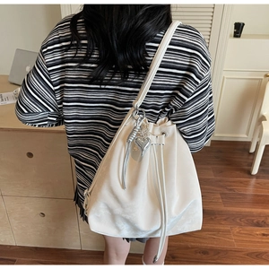 Detailed back view of a white drawstring bucket bag with silver heart charm and metal spiral