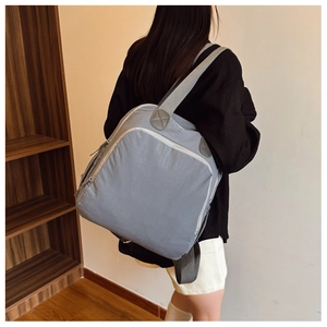 Mochila gris de nailon para mujer vista desde atrás en modelo en un interior acogedor