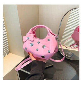 Détail du sac bandoulière rose avec rivets argentés et nœud décoratif latéral