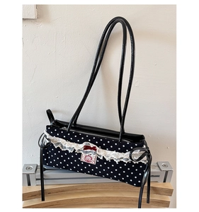 Détail du sac à bandoulière à pois avec dentelle et un nœud en velours rouge
