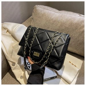 Detail of black quilted leather bag with gold chain strap and metallic turn-lock closure