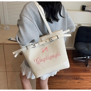 Détail d'un grand sac cabas crème avec broderie nœud rose et boucle décorative élégante