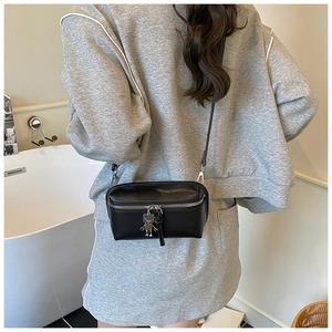Detail of a black leather mini box crossbody bag with a unique silver robot metal charm