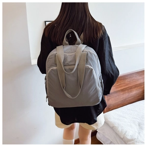 Mochila de nailon gris para mujer, vista trasera con amplios compartimentos y diseño minimalista