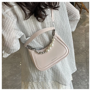 Détail d'un sac en cuir PU abricot clair avec chaîne en perles et lettrage de marque