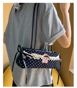 Détail du sac à bandoulière à pois noir et blanc avec nœud rouge et dentelle sur mannequin