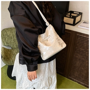 Glossy white shoulder bag with butterfly patterns and pearl bow detail shown on a model