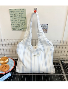 Detail view of a large capacity blue and white striped canvas tote bag on a wall hook