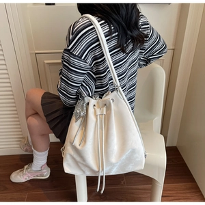Close-up of white bucket bag with silver heart charm and adjustable slim shoulder strap