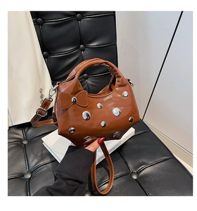 Détail du sac seau marron brillant avec clous argentés et nœud décoratif en cuir